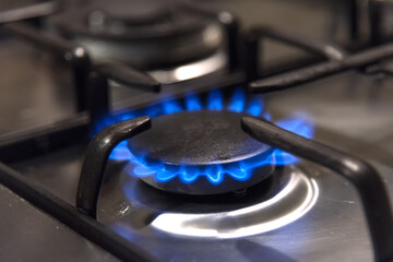 Natural gas burns in blue on a home metal stove in the kitchen - blurred background, selective...
