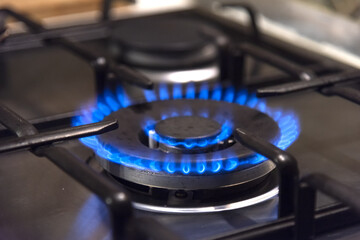 Natural gas burns in blue on a home metal stove in the kitchen - blurred background, selective focus, fuel shortage, gas shutdown, europe without gas, russian gas, cold winter