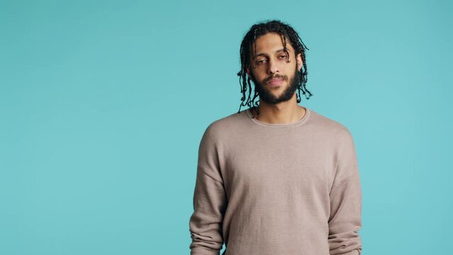 Uncaring middle eastern man shrugging shoulders, showing indifference and apathy. Careless BIPOC person doing nonchalant indifferent hand gesturing, isolated over studio background, camera A