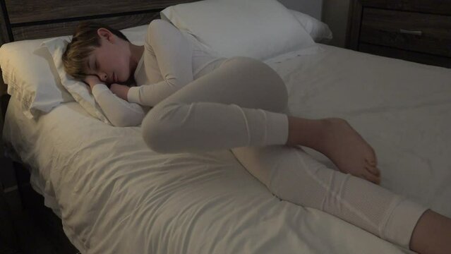 Boy in long white thermal pajamas sleeping tossing in his sleep