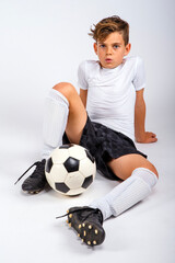 Male youth soccer player whistling while sitting on the floor with soccer ball