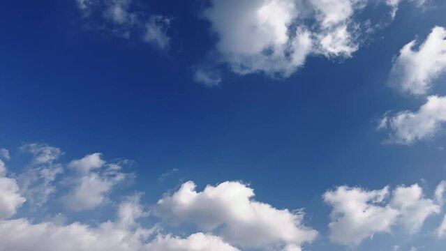 Swelling white cumulus clouds flowing and flying away in the blue sky. Cloudscape time-lapse footage.