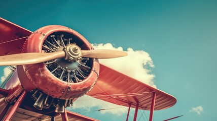 A close-up of a vintage biplane's red propeller and engine set against a clear sky