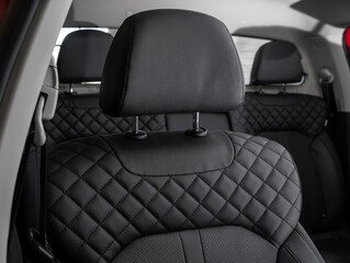 Close-up  leather black  rear seat made of  in the background passenger seats with seat belts. Luxury car interior