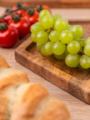 Close-up of a wooden oak plate with vegetables and bread in the background