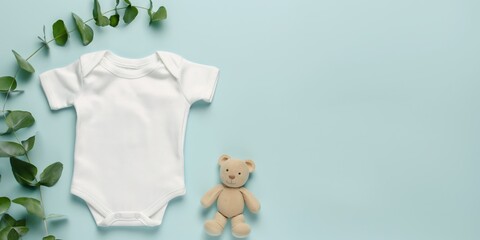 Flat lay of a white cotton baby short sleeve bodysuit accompanied by natural wooden and soft fabric toys on a light blue background, depicting a clean and nurturing setting.