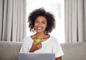 Woman, apple and laptop on sofa for snack, wellness or diet for break, vitality or eat for health...