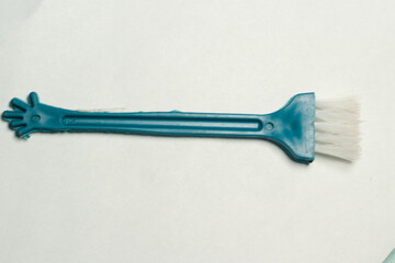 A small blue dust cleaning brush with white bristles