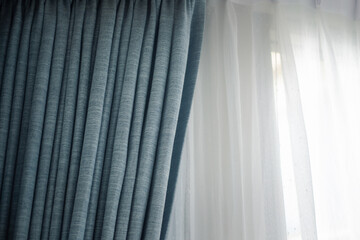 Light coming through a sheer, transparent and pleated light curtains or drapes. Window with drapes covering it