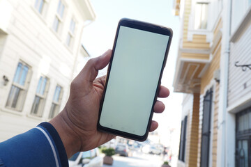 young man hand using smart phone with empty screen against city buildings 