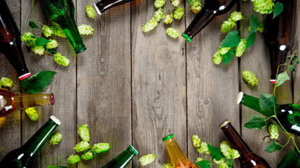 Beer and green hops. On wooden table. - obrazy, fototapety, plakaty