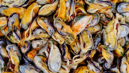 Close up fresh asian green mussel meat on a white plate on a brown wooden table. Clams on the serving plate. Rustic style. Banner with space for text