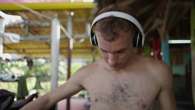 Shirtless man with headphones at ringside