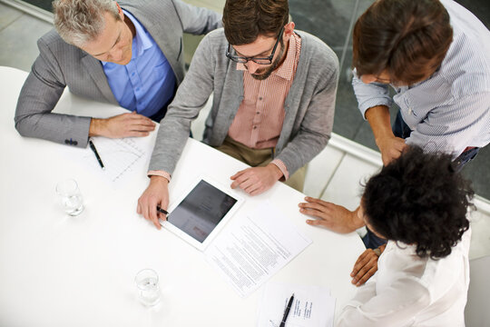 Business people, meeting and tablet screen above in teamwork for planning, discussion or collaboration at office. Top view of group or employees with technology in project on mockup at workplace