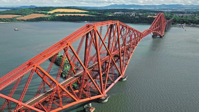 Aerial view of Forth Bridge, a long red railway bridge crossing the Forth estuary. Cantilever railway bridge carrying passengers and freight, cruise ship transporting tourists in Scotland.
