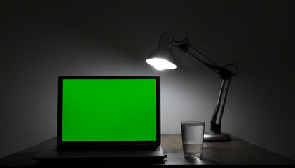 mock up. Laptop with blank green screen, and office on desk. Blank computer monitor on table with...