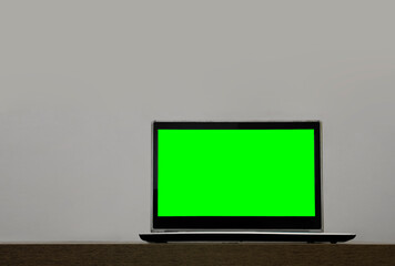 Laptop mock up with green blank mockup screen on wooden table isolated on white background. empty copy space. mock up laptop and studying office concept, empty white table stage with computer. mock-up