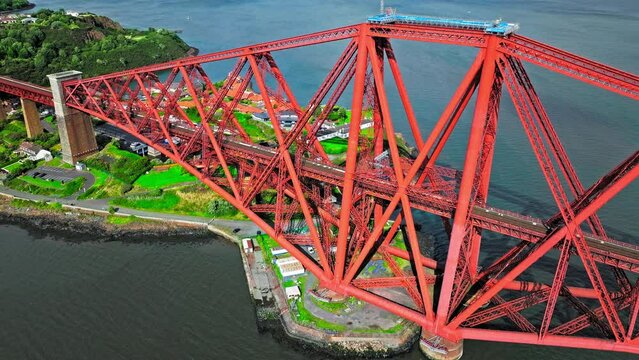 Aerial view of Forth Bridge, a long red railway bridge crossing the Forth estuary. Cantilever railway bridge carrying passengers and freight, cruise ship transporting tourists in Scotland.