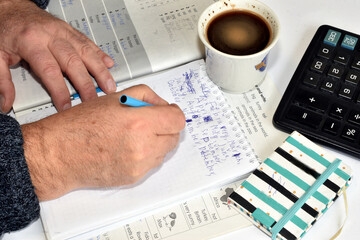 A man writes something in a notebook with a fountain pen.
