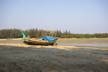 Obraz premium Local fishing boat on the beach. It is placed on the seaside at low tide. This place is known as Noakhali Musapur Closer or Musapur Sea Beach in Bangladesh. 