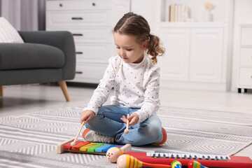 Little girl playing toy xylophone at home