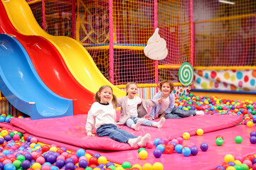 Happy kids playing in play room with slides, mats and ball pit