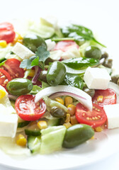Healthy Salad with Feta Cheese, Green Olives, Baby Spinach, Cucumber, Cherry Tomatoes and Capers. Bright background. Close up.	