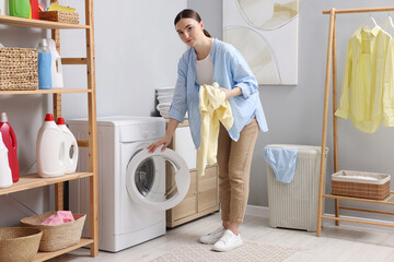 Beautiful woman with sweatshirt near washing machine in laundry room