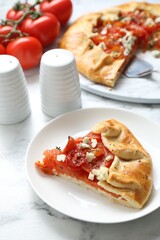 Tasty galette with tomato and cheese (Caprese galette) on white marble table, closeup