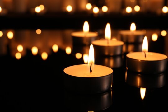Burning candles on dark surface. Memory day