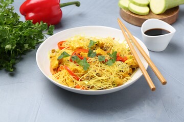 Stir-fry. Delicious cooked noodles with chicken and vegetables in bowl served on gray textured table