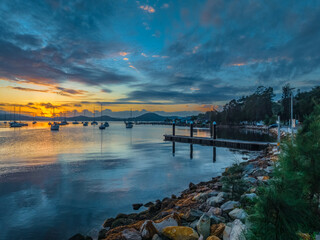 Aerial sunrise waterscape with boats, clouds and fog over the mountain range