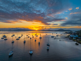 Aerial sunrise waterscape with boats, clouds and fog over the mountain range