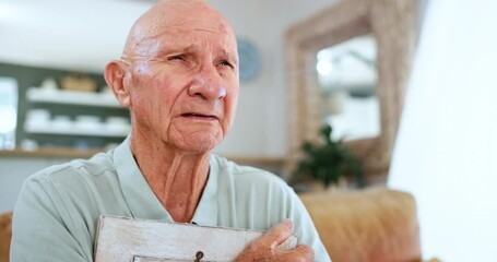 Senior man, home and cry with photo frame in sofa for memories with grief, lonely and emotional for loss. Widower, living room and sorrow for pain in couch with thoughts for love and anniversary