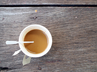milk coffee in portable paper coffee cup on grunge hardwood desk floor