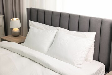 Soft white pillows and duvet on bed at home