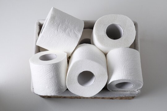 Toilet paper rolls in basket on white table, top view