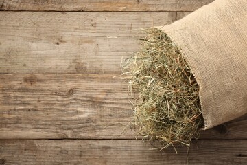 Burlap sack with dry herb on wooden table, top view. Space for text