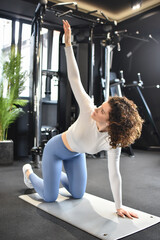 Sportive young woman in a gym training. Working out in a fitness gym. Flexible young woman exercises in the gym