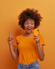 Joyful young woman with curly hair showing smartphone and having an idea