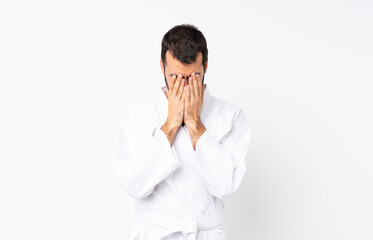 Young man doing karate over isolated white background with tired and sick expression