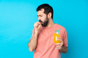 Young man over holding a cocktail over isolated blue background is suffering with cough and feeling...