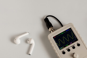 Wireless headphones and oscilloscope close-up on a light background