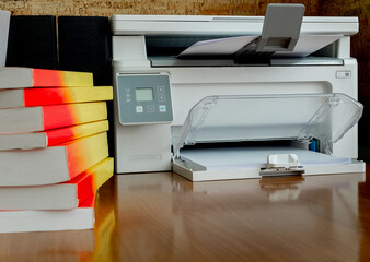 printer and a stack of books on his desk. Office concept