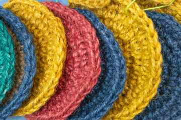 Multi-colored hand-knitted jute rugs lie one after another photographed close up with texture.
