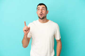 Fototapeta premium Young handsome caucasian man isolated on blue background thinking an idea pointing the finger up