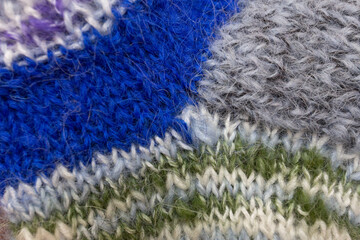 The texture of a sock knitted from different colors of wool close up.