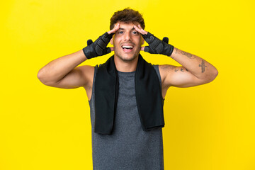 Young sport caucasian man with towel isolated on yellow background with surprise expression