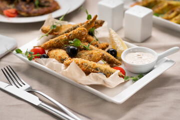 Goby fish or anchovy fried in breadcrumbs served with sour cream sauce in a restaurant