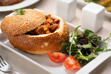 meat goulash in a loaf of bread served on a white plate in a restaurant. Traditional Hungarian cuisine